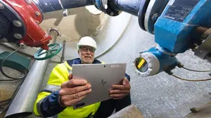 Ein Monteur sitzt in einem leeren Trinkwasserbrunnen und kontrolliert die Geräte.