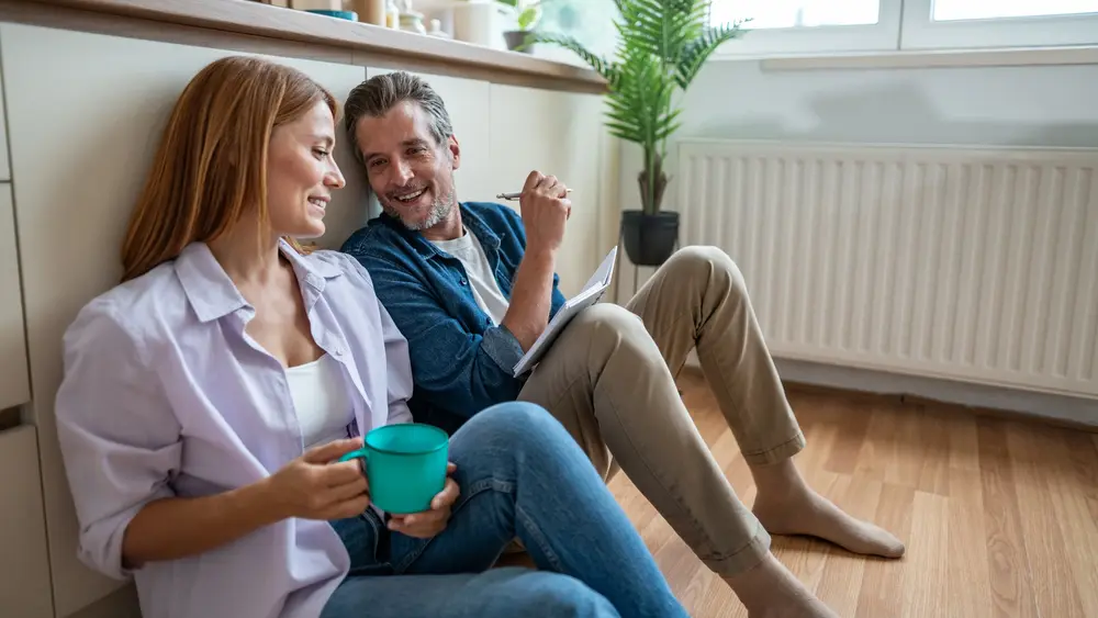Mann und Frau im Gespräch vor einer Heizung