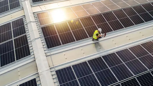 Photovoltaik-Dachanlage mit Monteur Ein Monteur steht auf dem Dach von einem Gewerbe zwischen Photovoltaik-Dachanlagen.
