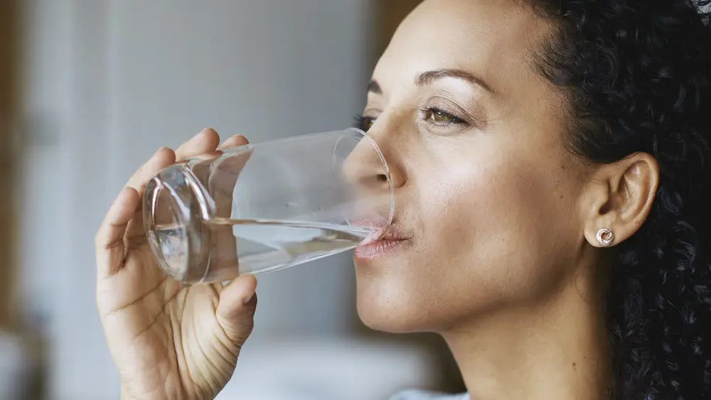 Frau trinkt Wasser aus einem Glas