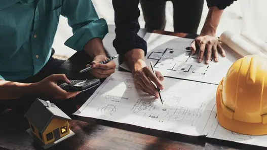 Erstklassige Schutz- und Sekundärtechnik für einen sicheren Betrieb Zwei Planer arbeiten an einem Tisch mit Anlagenplänen an einem maßgeschneiderten Konzept zur Schutz- und Sekundärtechnik von Anlagen.