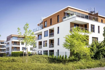 Mehrfamilienhäuser Springbach Höfe Mehrfamilienhäuser Neubauten in weiß und Holztönen in einer modernen Wohnsiedlung bei gutem Wetter