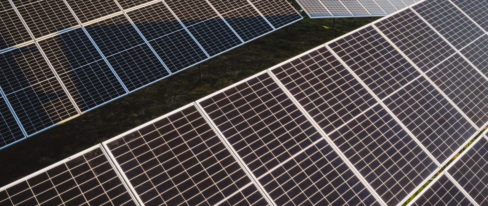 Ein großer Solarpark mit vielen Photovoltaikanlagen befindet sich auf einem Feld in der Sonne.