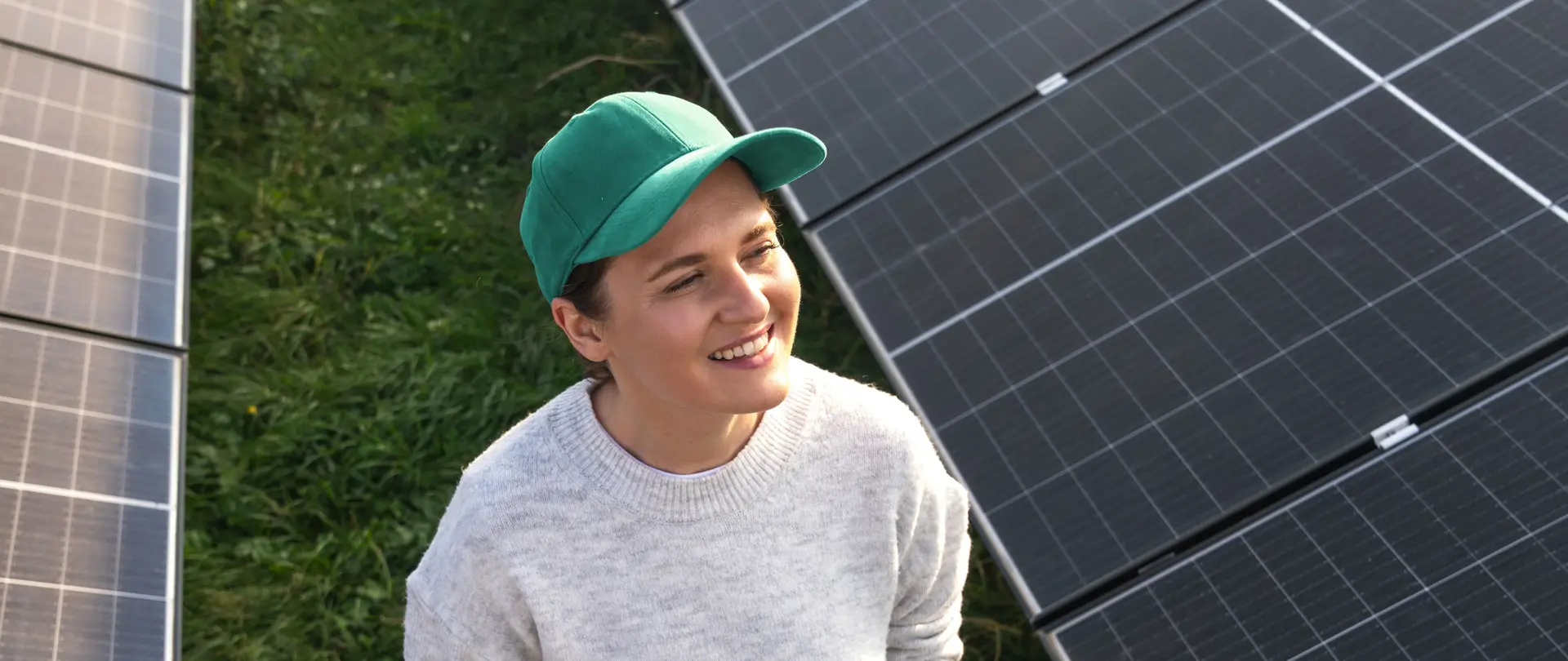 Eine Frau läuft durch ein Feld mit Photovoltaikanlagen mit einem Tablet in der Hand und lächelt.