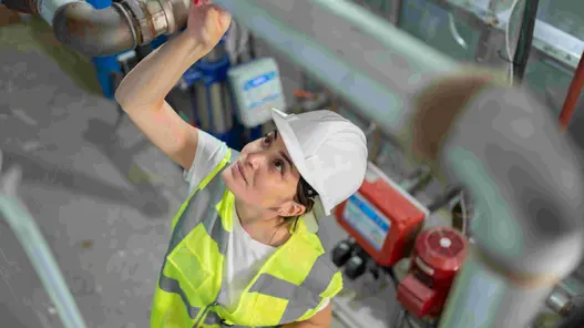 Kontrolle der Wasserleitungen durch eine Monteurin.