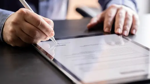 Datenschutz Vertrag Eine Person unterschreibt ein digitales Dokument auf einem Tablet mit einem Stift.