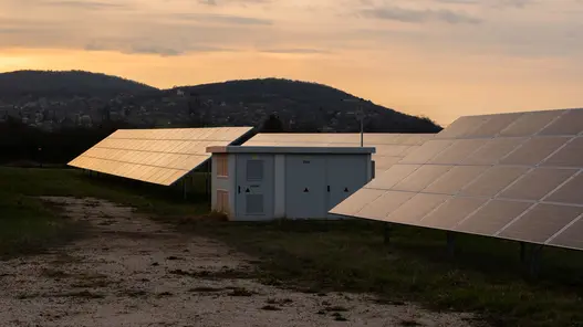 Trafostationen für Industrie und Gewerbe Eine Trafostation steht in einem Feld umgeben von Photovoltaikanlagen.