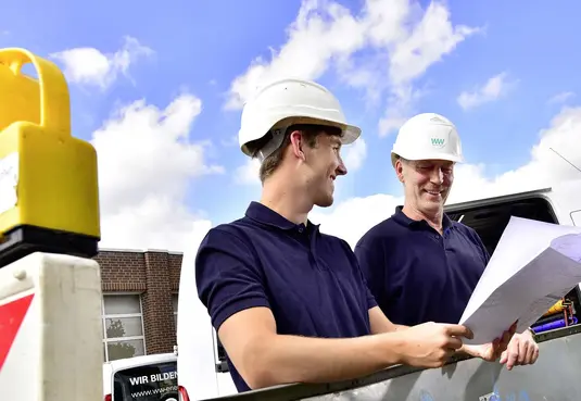 Zwei Monteure mit Helm an einer Baustelle