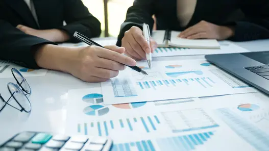 Prognose von Batteriespeichern Zwei Personen analysieren Diagramme und Tabellen zu Energiespeichern in einem Besprechungsraum mit Laptop und Unterlagen.