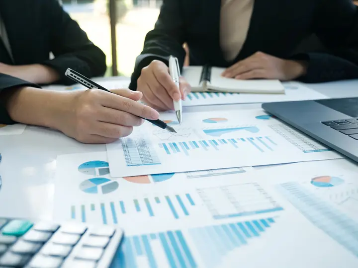 Prognose von Batteriespeichern Zwei Personen analysieren Diagramme und Tabellen zu Energiespeichern in einem Besprechungsraum mit Laptop und Unterlagen.