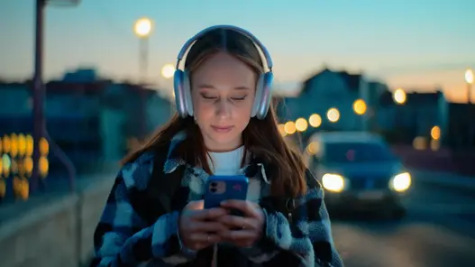 Infrastruktur Header Mädchen mit Handy und Beleuchtung Mädchen schaut aufs Handy und geht eine Straße entlang