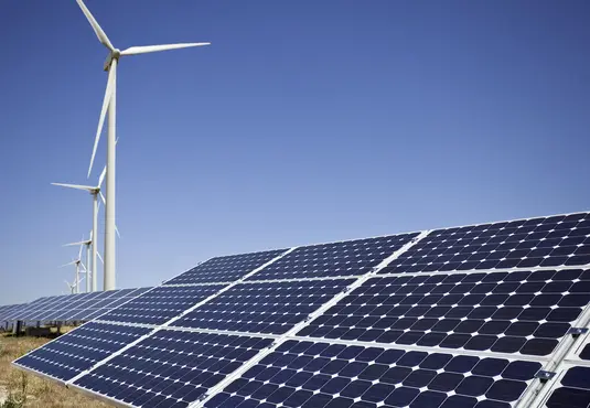 Solar-Panel mit Windrädern im Hintergrund