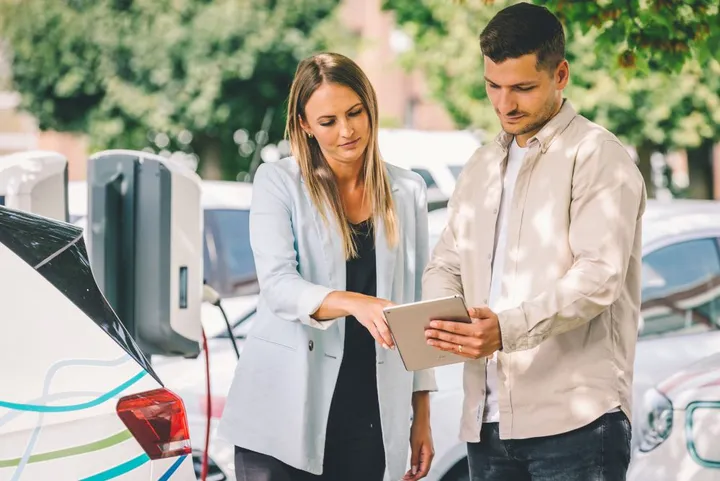 Ladeservice Wallbox Frau und Mann stehen vor einer Wallbox und einem Elektroauto