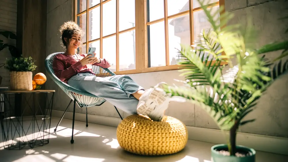 Frau sitzt am Fenster und genießt Wärme