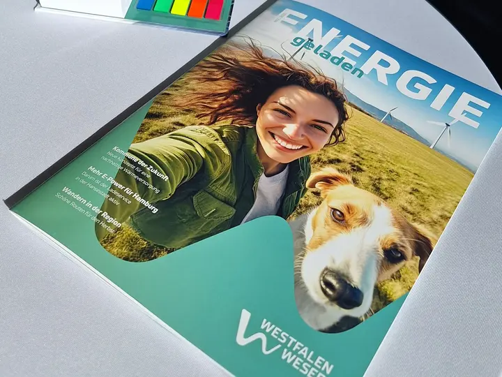 Zweite Ausgabe des Kundenmagazins ENERGIEgeladen Der Titel der zweiten Ausgabe des Kundenmagazins ENERGIEgeladen zeigt eine Frau mit ihren zwei Hunden auf einer Wieso vor Windkraftanlagen.