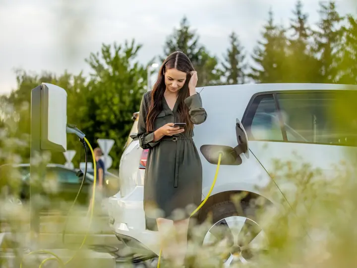 Ladehardware für komfortables Elektroauto‑Laden Eine Person steht neben einem ladenden Elektroauto an einer öffentlichen Ladestation.
