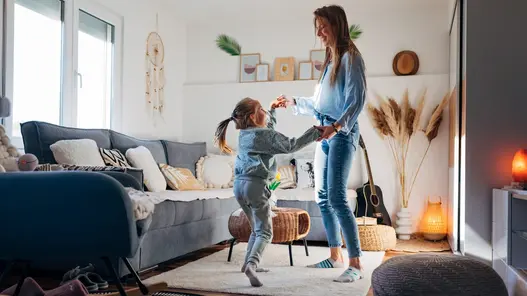 Mutter und Tochter im Wohnzimmer Eine Mutter tanzt mit ihrer Tochter in einem schön eingerichteten Wohnzimmer